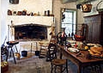 A colonial country kichen with fireplace and utensils.